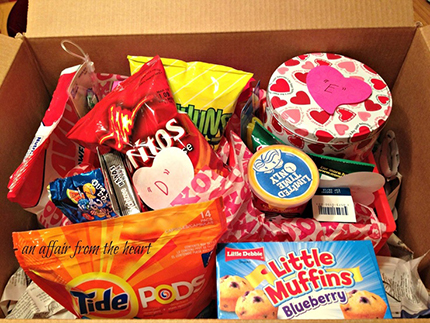 An opened care package box with snack food items inside